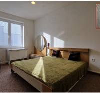 Hálószoba franciaággyal, zöld takaróval, éjjeliszekrénnyel és tükörrel egy családi házban.