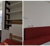 A családi házban fehér szekrények, egy munkasztal és egy piros kanapé van.