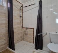 Fürdőszoba egy családi házban egyszerű zuhanyzóval és világos csempékkel.