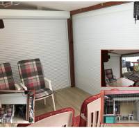 Családi ház nyári terasza ülőgarnitúrával és fa dekorációjú padlóval.