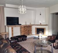 Nappali kandallóval egy családi házban, bőrfotel és dohányzóasztal.