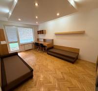 Nappali egy háromszobás lakásban, fa dekoros padlóval és íróasztallal.