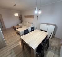 Nappali fa mintázatú padlóval, kanapéval és asztallal egy háromszobás lakásban.