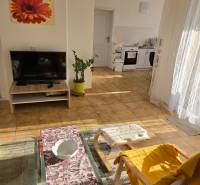 Családi ház nappalija kanapéval, televízióval és kilátással a konyhára.