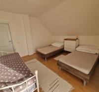 Hálószoba családi házban három ággyal és fa dekorációjú padlóval.