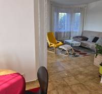 Nappali egy családi házban ablakkal, sárga fotellel és asztallal.