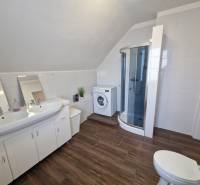 Fürdőszoba családi házban mosdóval, zuhanyzóval és fa dekoros padlóval.