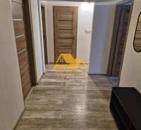 Folyosó egy háromszobás lakásban, fa dekorációjú padlóval és több ajtóval.