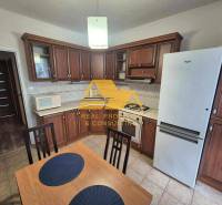 Konyha sötét fa dekorációval, tűzhellyel és hűtőszekrénnyel egy háromszobás lakásban.