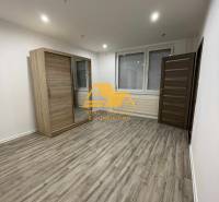 Tágas szoba tolóajtós szekrénnyel és fa dekoros padlóval egy egyszobás lakásban.