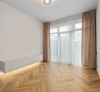 Nappali egy kétszobás lakásban, fa mintázatú padlóval és fehér bútorokkal.