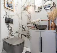 Fürdőszoba egy kétszobás lakásban márvány falakkal, stílusos mosdóval és dekorációkkal.