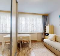 Nappali egy háromszobás lakásban kanapéval, asztallal és fa dekorációjú padlóval.