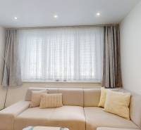 Nappali kanapéval és függönyökkel egy háromszobás lakásban.