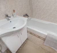 Fürdőszoba egy háromszobás lakásban káddal, mosdóval és csempével.