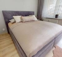 Hálószoba egy háromszobás lakásban, fa dekoros padlóval, ággyal és erkéllyel.