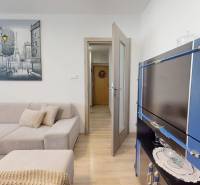 Nappali egy háromszobás lakásban sarokkanapéval és fa dekorációjú padlóval.