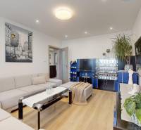 Nappali egy háromszobás lakásban, dekoratív képpel és fa dekorációjú padlóval.