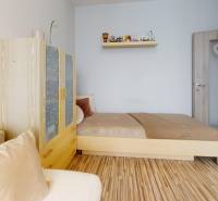 Szoba ággyal, szekrénnyel és fa dekorációjú padlóval egy háromszobás lakásban.