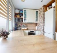 Konyha egy 3 szobás lakásban, világos konyhabútorral és fa hatású padlóval.