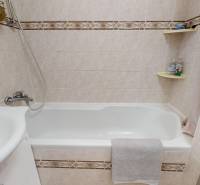 Fürdőszoba káddal és mosdóval egy háromszobás lakásban, világos csempével burkolva.