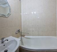 Fürdőszoba egy kétszobás lakásban káddal, mosdóval és tükörrel, bézs csempével burkolva.