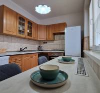 Konyha fa szekrényekkel és étkezőasztallal egy kétszobás lakásban.