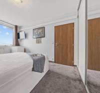 Világos hálószoba ággyal, nagy ablakkal és gardróbszekrénnyel egy kétszobás lakásban.