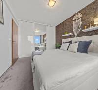 Hálószoba egy kétszobás lakásban franciaággyal, tükrös szekrénnyel és faldekorációkkal.