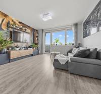 Nappali kényelmes kanapéval, növényi mintás tapétával és fa dekorációjú padlóval.