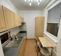 Konyha egy egyszobás lakásban minimalista asztallal és világos bútorokkal.