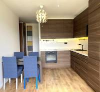 Konyha egy háromszobás lakásban étkezőasztallal, modern világítással és fa dekorációjú padlóval.