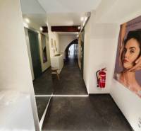 Kereskedelmi helyiségek folyosója plakáttal, fa dekoros padlóval és tűzoltó készülékkel.