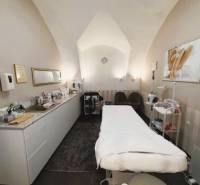 Üzlethelyiség masszázsággyal, gyógyászati segédeszközökkel és dekoratív képpel a falon.