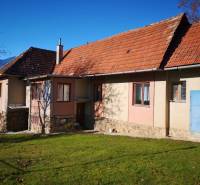 Családi ház Kalamenyben, Rózsahegyen, piros tetővel és kék ajtókkal.