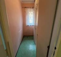 Keskeny szoba beépített szekrénnyel és függönnyel egy háromszobás lakásban.