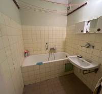 Fürdőszoba egy háromszobás lakásban káddal, mosdóval és csempézett falakkal.