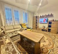 Nappali egy kétszobás lakásban szőnyegekkel, ülőgarnitúrával és televízióval.