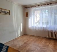 Szoba ablakkal és fa dekorációjú padlóval egy háromszobás lakásban.