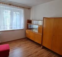 Szoba egy háromszobás lakásban régi bútorokkal és fa dekorációjú padlóval.