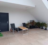 Erkély egy 2 szobás lakásban terasszal, székekkel és növényekkel.