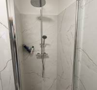 Zuhanykabin márvány burkolattal egy kétszobás lakásban.