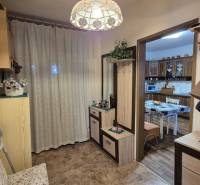 Családi ház előszobája fogassal, tükörrel és bejárattal a konyhába, ahol étkezőasztal található.