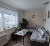 Nappali egy családi házban kanapéval, asztallal és függönyös ablakkal.