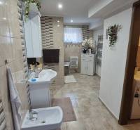 Fürdőszoba családi házban csempézett fallal, bidével, mosógéppel és dekorációkkal.