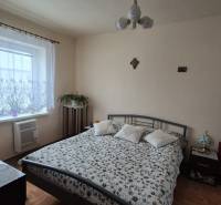 Hálószoba családi házban mintás ágytakaróval, televízióval és fa dekorációjú padlóval.