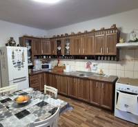 Konyha családi házban konyhabútorral, étkezőasztallal és fa dekoros padlóval.