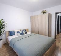 Hálószoba egy kétszobás lakásban ággyal, szekrénnyel és fa dekorációjú padlóval.