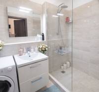 Fürdőszoba egy kétszobás lakásban, modern zuhanyzóval és dizájnos mosdószekrénnyel.