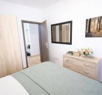 Hálószoba egy kétszobás lakásban szekrénnyel, komóddal és fa dekor padlóval.